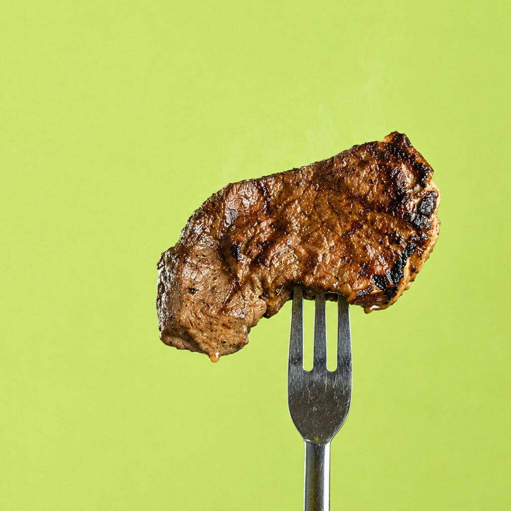 A grilled steak on a fork against a bright green background, symbolising unpacking the key changes and talking points from the Federal Budget 2026 -27 for businesses and individuals.